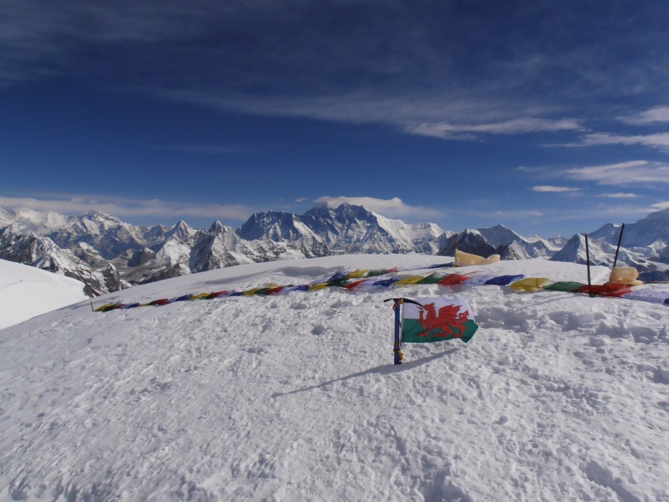 Flags on the summit of Mera Peak with a view of Everest in the background