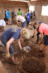 Staff and students mixing concrete for a floor.